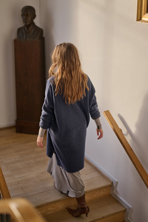 Woman walking up a staircase in a room with a bust on a pedestal.