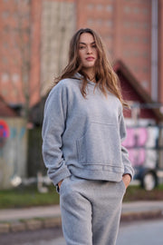 Woman wearing a gray hoodie and pants standing outdoors with blurred background