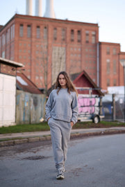 Person in a gray outfit walking on a street with industrial buildings in the background