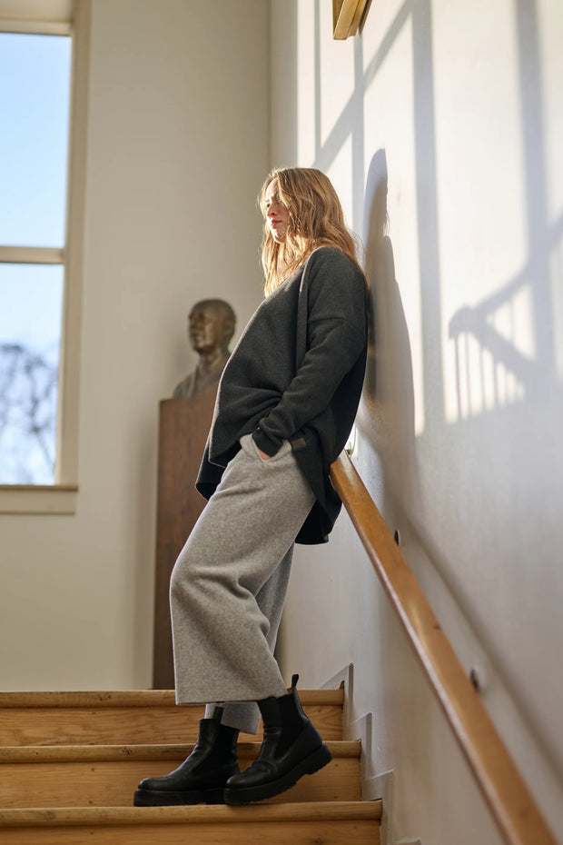 Woman standing on a staircase in a well-lit room with large windows.