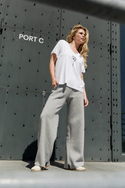 Woman in white top and gray pants standing in front of a large metallic door with 'PORT C' text.