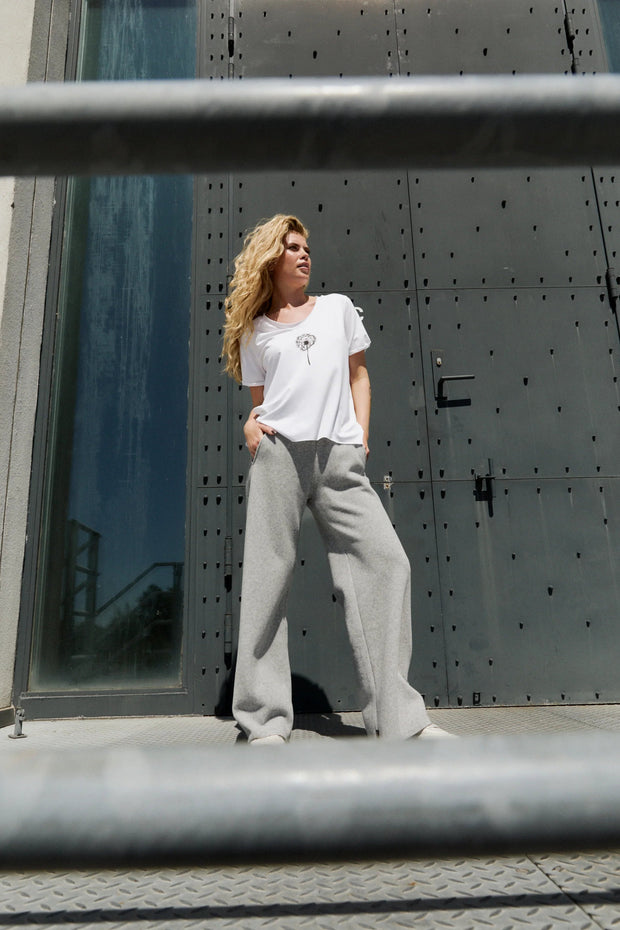 Person wearing a white t-shirt and gray sweatpants standing in front of a large metallic door.