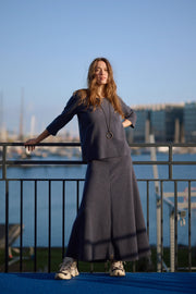 Woman in a navy outfit standing on a balcony with a waterfront view