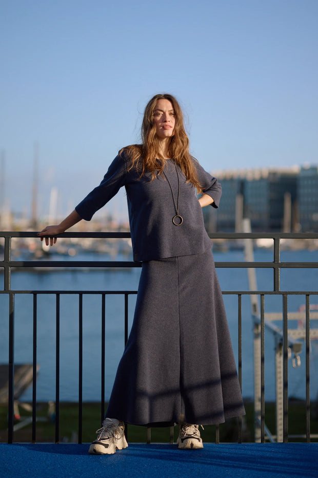 Woman in a navy outfit standing on a balcony with a waterfront view